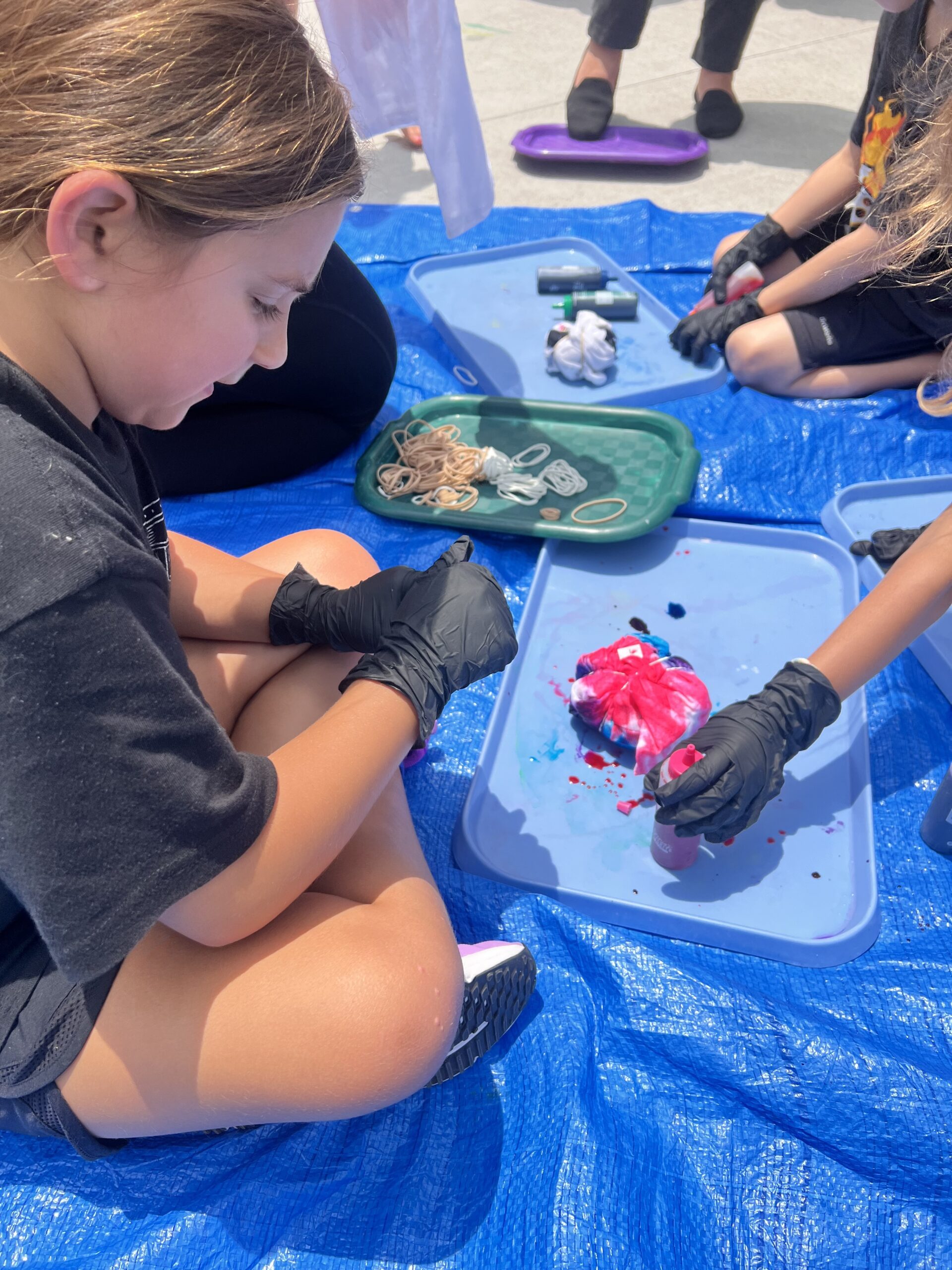 Group of kids tie dying shirts.
